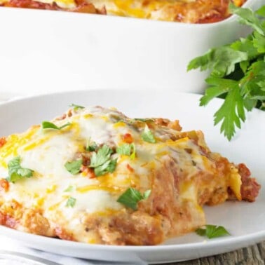 Angled view of a slice of Cajun Shrimp Lasagna on a white serving dish.