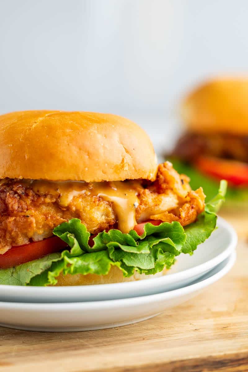 A crispy chicken sandwich on a white plate.