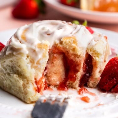 side view of strawberry roll on plate with bite taken out of it